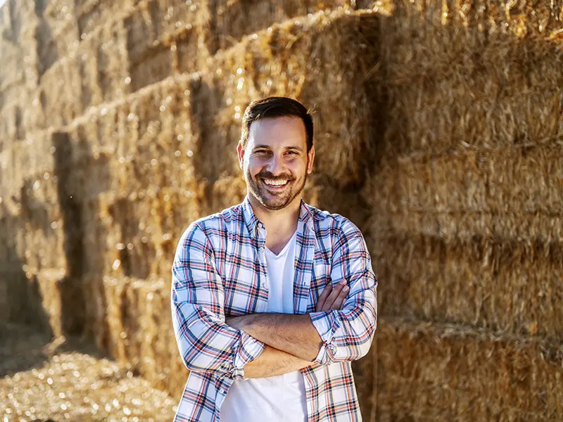 smiling farmer in front of hay